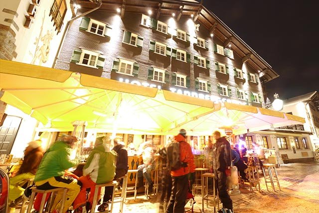 People sitting outside an apres ski bar at night