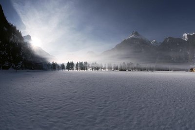 Mist rising over a snowy valley at sunrise